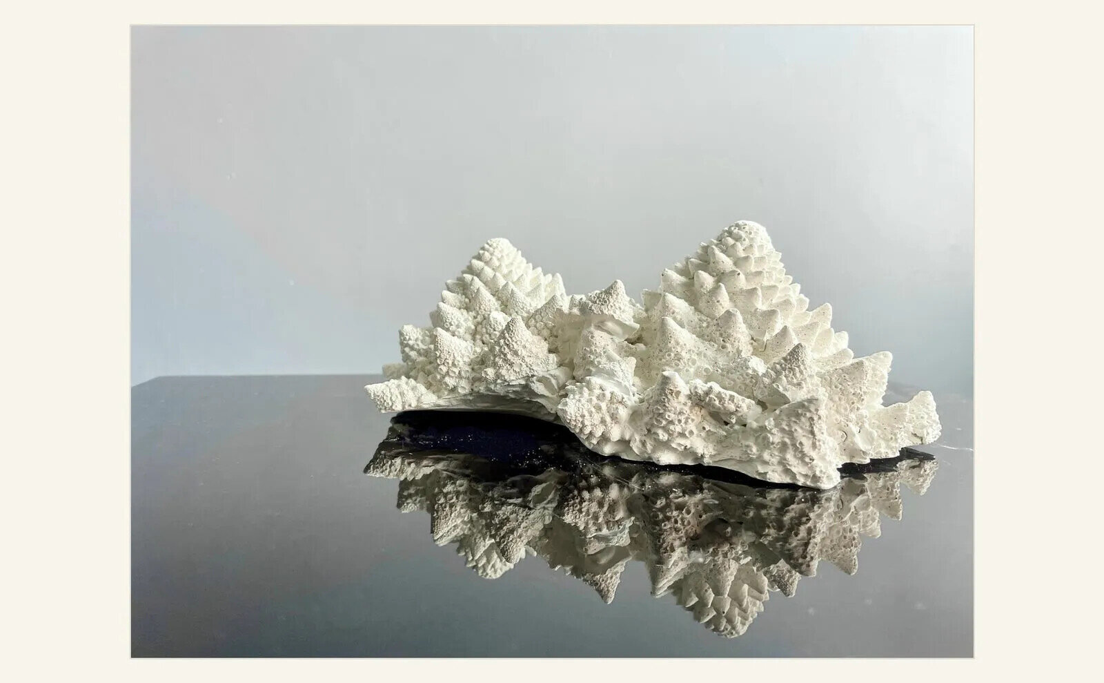 Jasmine Pradissitto, Monticulus, 2025, a pale NOXORB sculptural form displayed on a reflective dark surface and made with material designed to absorb nitrogen oxides.