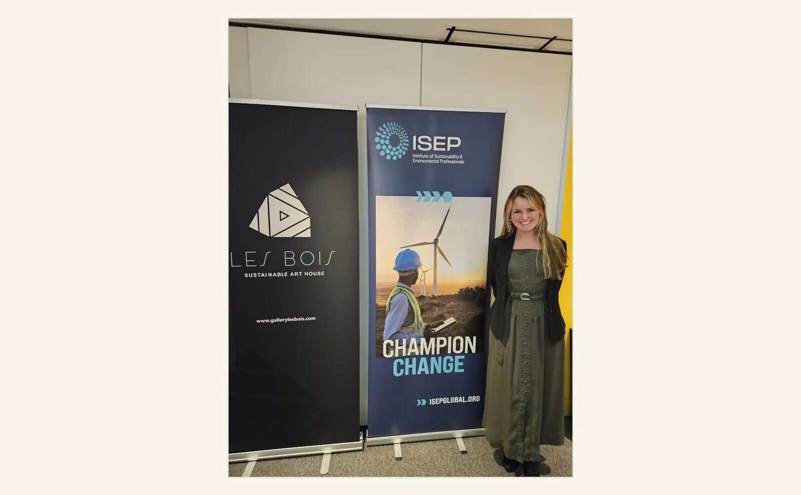 Claire-Julia Hill beside exhibition and ISEP banners at a sustainable art discussion.